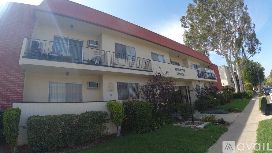 A two-story apartment building with balconies and a red roof.