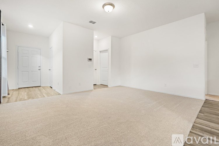 A spacious, empty room with white walls and a carpeted floor.