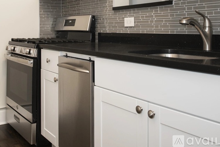 A modern kitchen with a black countertop and white cabinets.