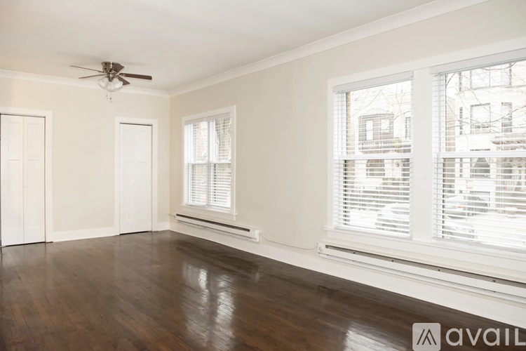 A room with a ceiling fan and two windows with blinds.