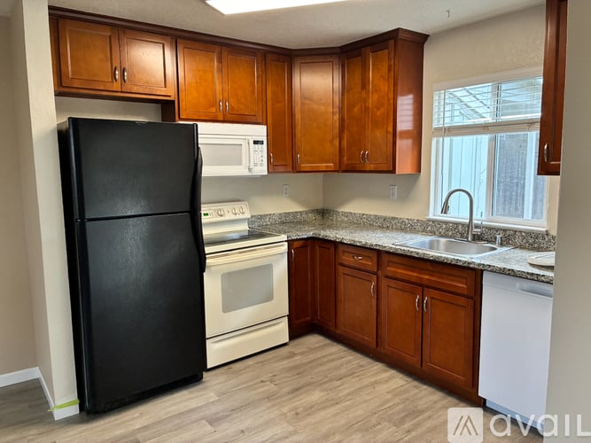 A kitchen with a black fridge, white oven, and wooden cabinets.