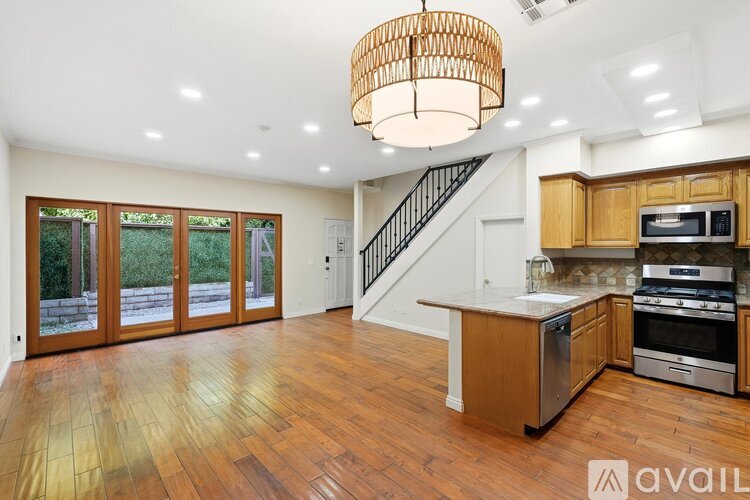 A large open kitchen and living room with wood floors and a staircase.