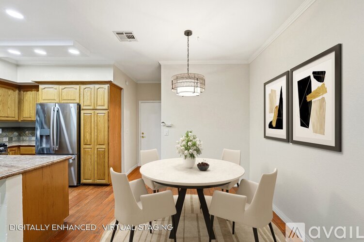 A dining room with a white table and chairs, a chandelier, and a framed picture on the wall.