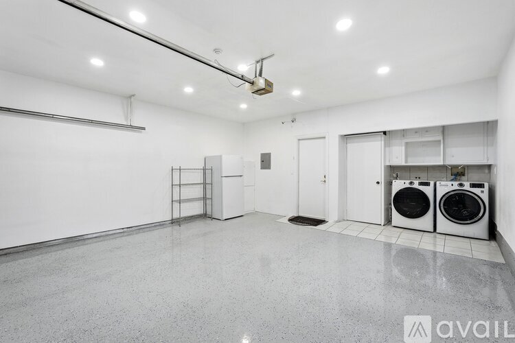 A spacious, empty room with a washer and dryer set up.