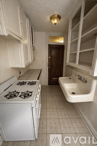 A kitchen with a white stove top oven and a white sink.
