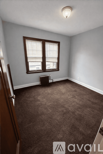 A room with brown carpet and a window with blinds.
