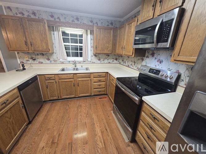 A kitchen with wooden cabinets and a floral wallpaper.
