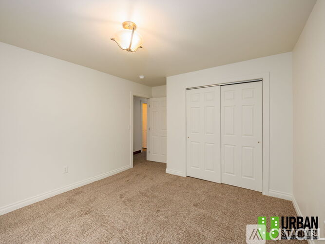 A white bedroom with a carpeted floor and a white door.