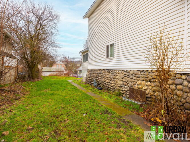 A house with a stone wall and a grassy area in front.