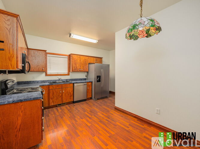 A kitchen with wooden cabinets and a stainless steel refrigerator.
