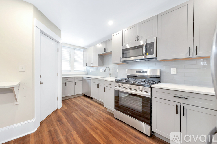 A kitchen with white cabinets and a wooden floor.