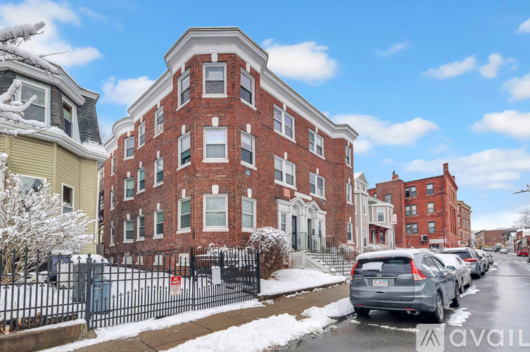 A row of houses with a car parked in front of the red brick building.