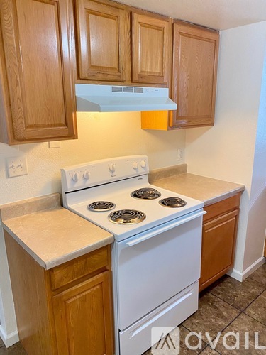 A kitchen with wooden cabinets and a white stove top oven.