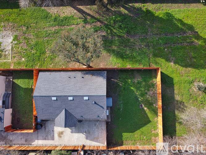 A house with a grey roof is surrounded by a grassy area.