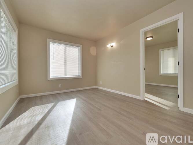 A spacious room with a window and a door leading to another room.
