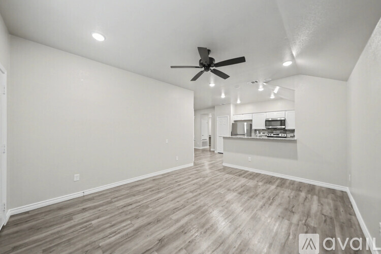 A spacious room with a ceiling fan and wooden flooring.