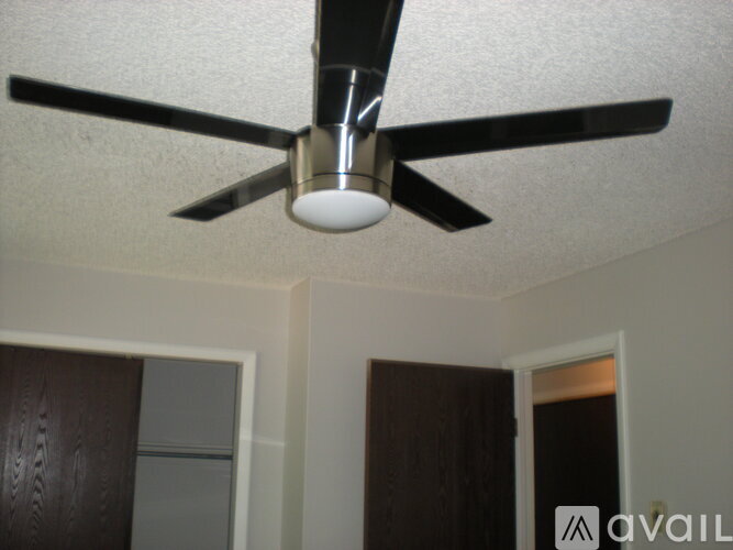 A ceiling fan with a light fixture is mounted in a room with white walls.
