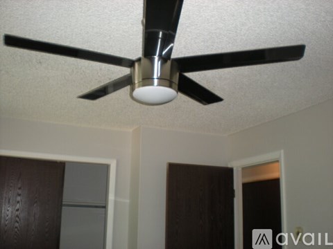 A ceiling fan with a light fixture is mounted in a room with white walls.