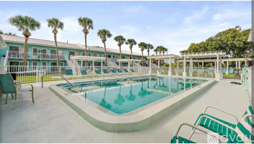 A large outdoor swimming pool surrounded by palm trees and lounge chairs.