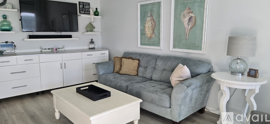 A living room with a grey couch, a white coffee table, and a white side table.