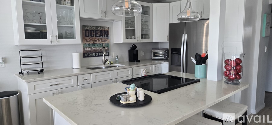 A kitchen with a white countertop and a black stove top.