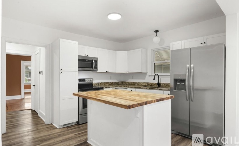 A kitchen with white cabinets and a wooden island.