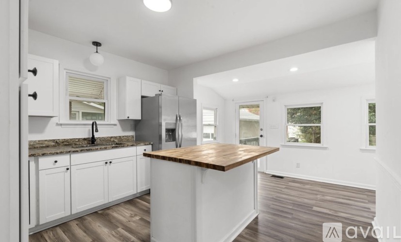 A kitchen with white cabinets and a wooden island.