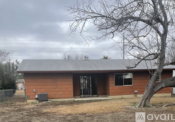 A house with a brown roof and a tree in front of it.