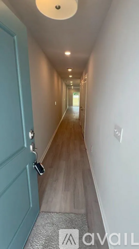 A long hallway with a blue door and a sign that says "available".