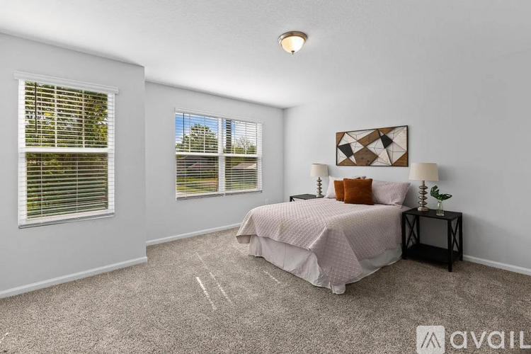 A bedroom with a bed, nightstand, and window with blinds.