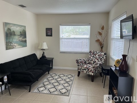 A living room with a black sofa, a patterned chair, and a painting on the wall.