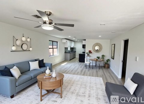 A living room with a grey couch, a wooden coffee table, and a ceiling fan.