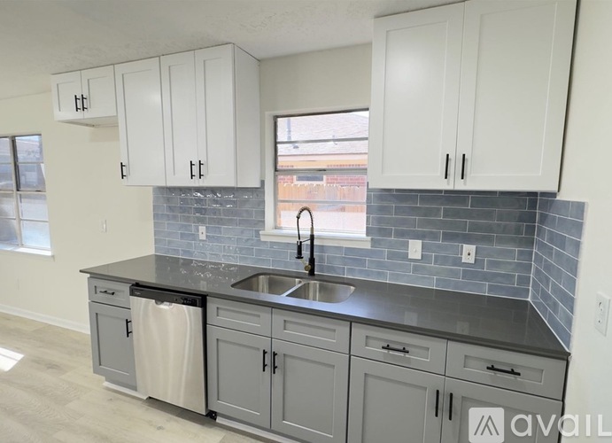 A kitchen with grey cabinets and a black countertop.