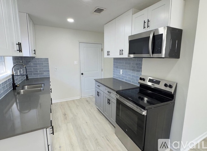 A kitchen with a stainless steel refrigerator, microwave, oven, and a tile backsplash.