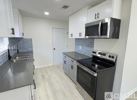 A kitchen with a stainless steel refrigerator, microwave, oven, and a tile backsplash.