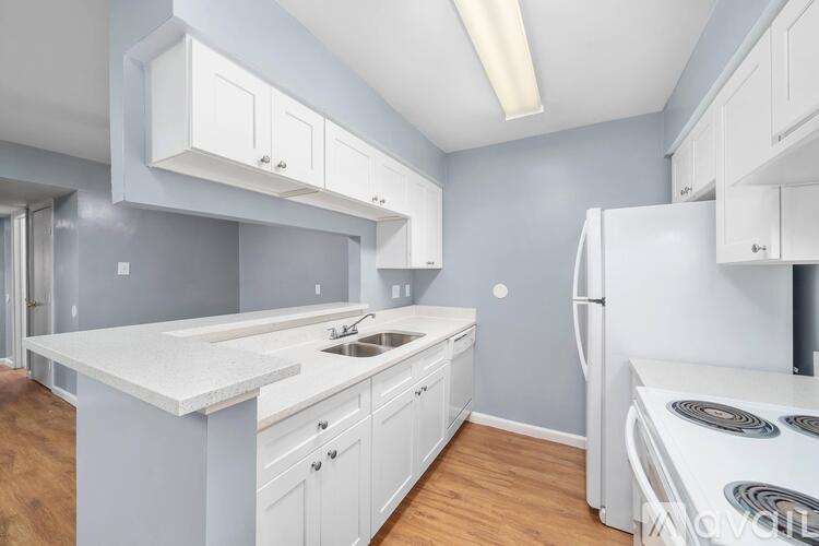 A kitchen with white cabinets and a white stove top oven.