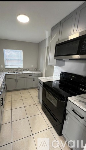 A kitchen with black appliances and white cabinets.