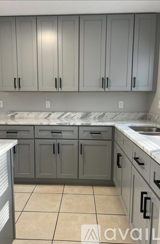 A kitchen with grey cabinets and a marble countertop.