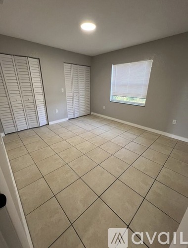 A room with beige tiled flooring and a window with blinds.