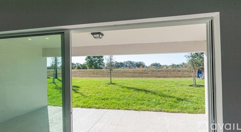 A view from inside a room looking out to a grassy area with a swing set.