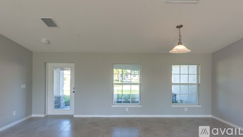 A spacious room with a door, a window, and a hanging light fixture.