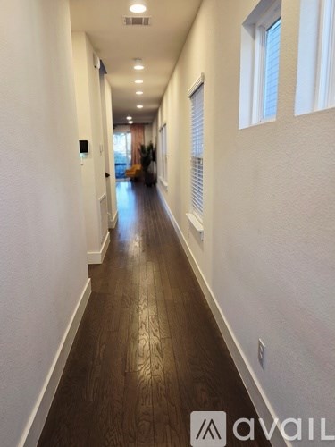 A long hallway with wood floors and white walls.