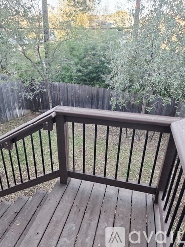 A wooden deck with a railing overlooking a grassy area.