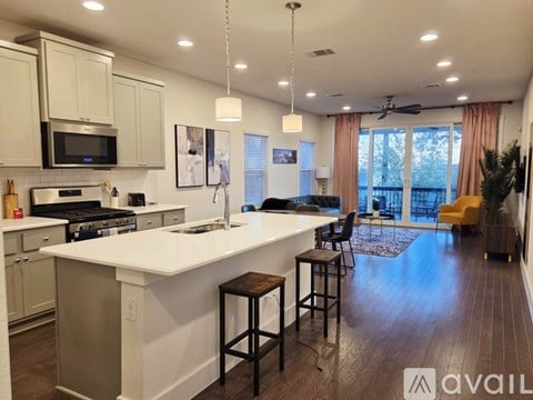 A modern kitchen with white countertops and stools.