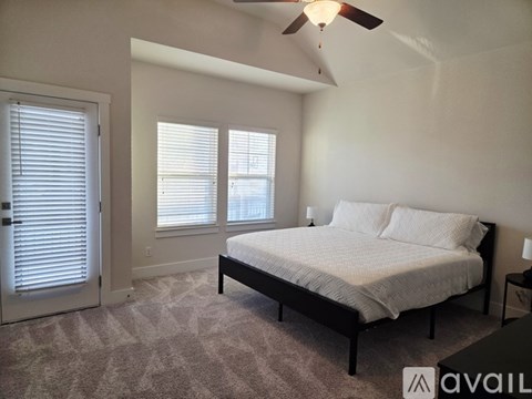 A bedroom with a bed, carpet, and a ceiling fan.