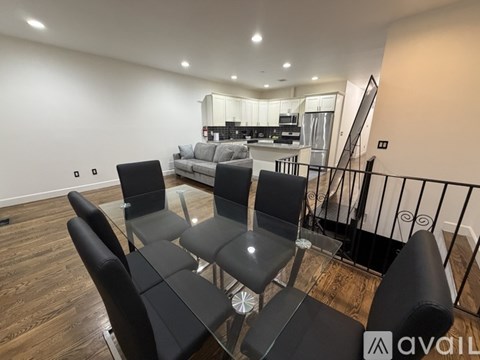 A living room with black chairs and a glass table.