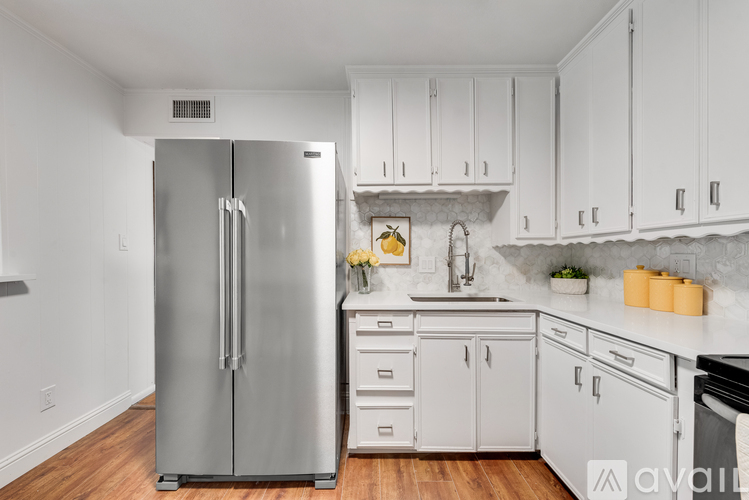 A modern kitchen with a stainless steel refrigerator and white cabinets.