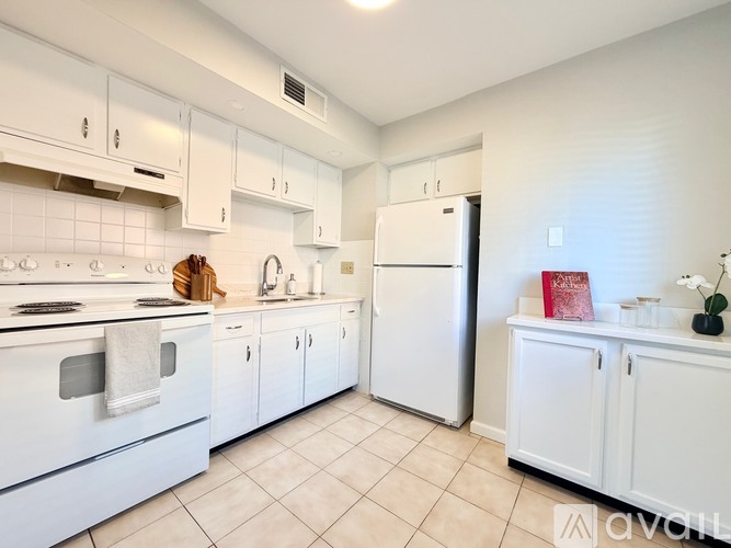 A white kitchen with a refrigerator, oven, and cabinets.