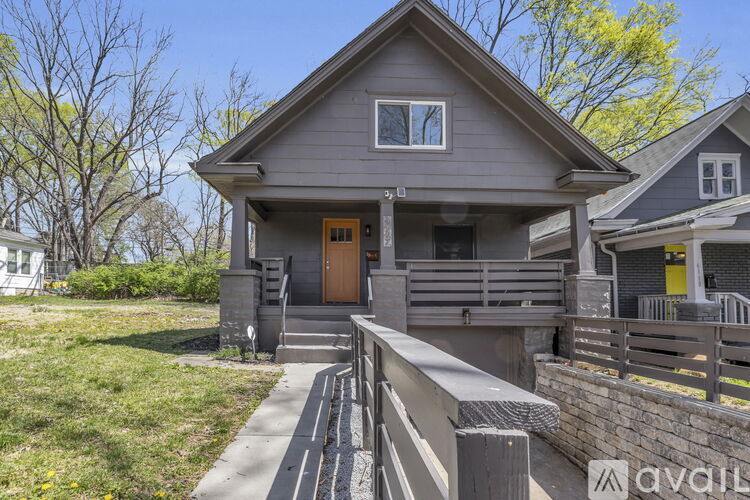 A house with a grey exterior and a brown door is for sale.