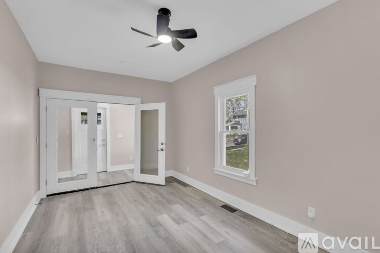 A room with a ceiling fan and a window showing an outdoor view.